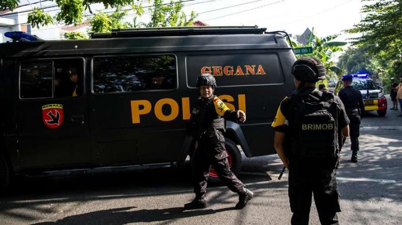 Indonesian policemen patrol outside a church following a suicide bomb