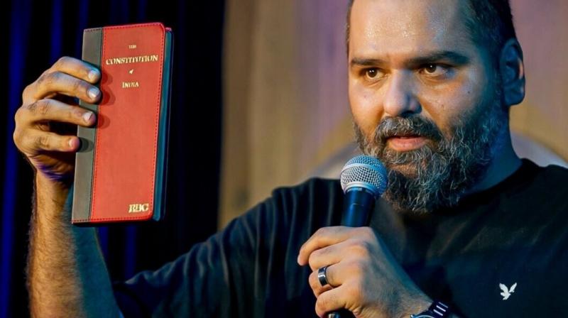 Kunal Kamra Refuses to Apologize; Eknath Shinde Reacts: ‘Satire Has Limits'. Comedian Kunal Kamra, at the end of show, holds up a copy of the Constitution of India during his stand-up special Naya Bharat. Emphasizing the importance of free speech, he remarks, “This allows me to do what I do. In the framework of this book, you can feel free to do anything.” Kamra’s statement highlights his belief in constitutional rights, particularly freedom of expression, amid ongoing debates about the limits of satire in India.